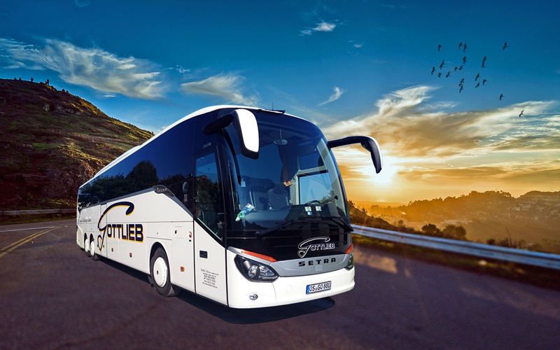 Reisebus fährt auf Straße. Sonnenuntergang im Hintergrund.